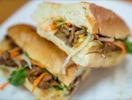 Grilled beef banh mi cut in half showing pickled vegetables