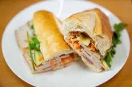 Banh mi cut in half with pork, pickled carrot and fresh herbs