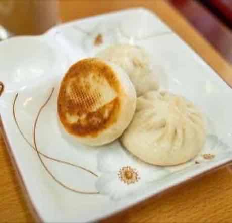 Golden pan-seared pork bun beside a steamed bun
