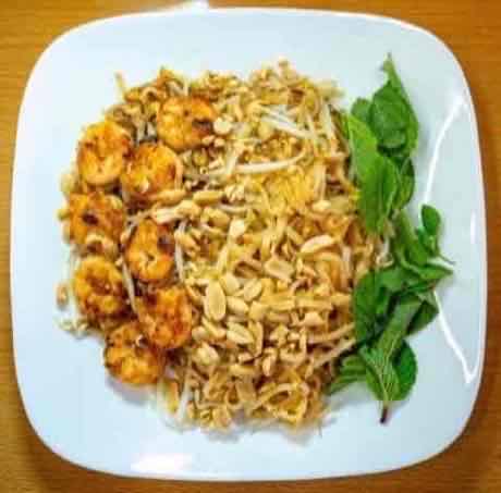 Plate of shrimp Pad Thai with peanuts and fresh mint